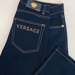 Dunkelblaue Jeans mit orangefarbenen Nähten und Versace-Logo auf der Rückseite.